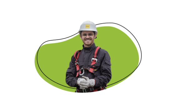 Fotografia de um jovem técnico de redes elétricas, vestido com o equipamento. de capacete e luvas. No fundo da foto, está uma mancha colorida em tom verde. 